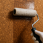 applying transparent fire retardant on cork walls with a paint roller leaving a shiny effect