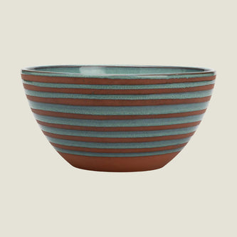 A round ceramic bowl with horizontal terracotta-colored and muted blue-green glazed stripes, shown against a plain white background.