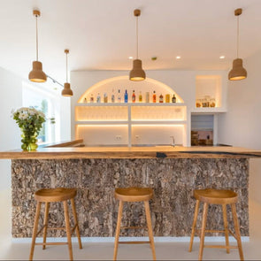 Modern kitchen with stone countertop, wooden stools, and pendant lights.