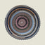 Round woven rug with concentric color patterns on a beige background