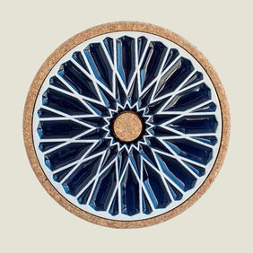 Round coaster with blue geometric design and cork back on a beige background