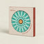 C° Atlánica hot pot stand in its original packaging, featuring a circular turquoise and white geometric design with a cork center, set against a warm beige background.