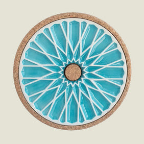Round coaster with blue geometric design and cork back on a beige background