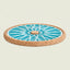 A round cork coaster with a light blue and white geometric wheel pattern, shown on a solid light beige background.