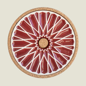 Round ceramic plate with red geometric design on a beige background