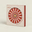 C Atlánica hot pot stand in its original packaging, featuring a circular window that reveals the red and white geometric star-patterned stand inside.