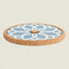 A round cork coaster with a light blue and white geometric floral pattern, shown on a solid light beige background.