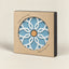 A ceramic pot base with a light blue and white geometric floral pattern and a cork center, presented in its kraft paper packaging with a circular cutout.