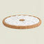 A round cork trivet or coaster with a white ceramic flower-shaped center, shown on a solid light beige background.