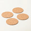 Four round cork coasters in natural tan color arranged in a loose square on a clean white background.