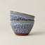Two stacked ceramic bowls with a speckled light blue and brown glaze, set against a plain beige background.