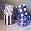 Set of four blue and white patterned mugs on a gray surface with a gray background